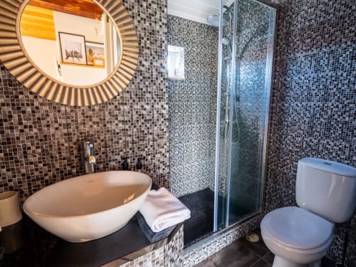 Modern bathroom at Villa Várzea with mosaic tile walls, vessel sink, shower, and round mirror in Várzea, Portugal