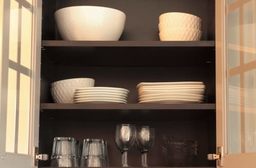 Glass cabinet in Villa Várzea Nomad Nest room displaying stacked white bowls, plates, and glassware