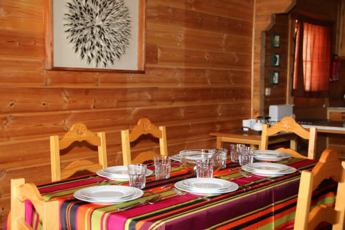 Sala de jantar da villa Cota 1500 com cadeiras de madeira, trilho de mesa colorido, arranjos de lugar e ambiente aconchegante de refúgio na montanha