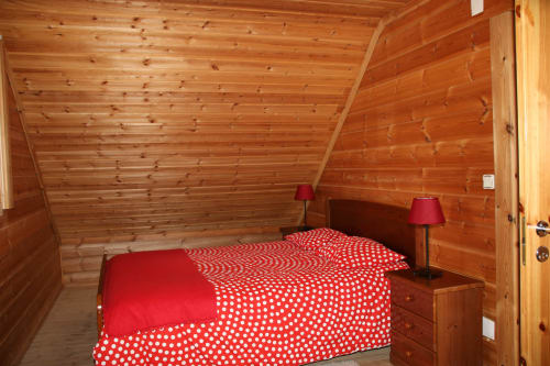 Quarto aconchegante em chalé de madeira na Cota 1500 com roupa de cama vermelha com bolinhas e vista para as montanhas