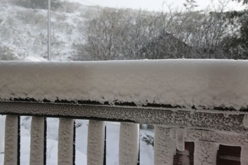 Varanda e corrimão cobertos de neve com vista para a floresta de montanha invernal na villa Cota 1500 em Penhas da Saúde