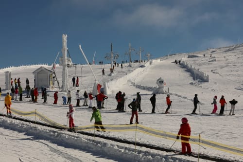 Estação de esqui nevada em Penhas da Saúde com esquiadores, teleféricos e lodge de montanha em paisagem invernal
