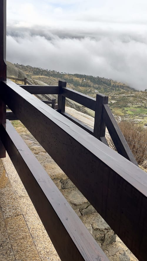 Varandim de madeira escura em varanda com vista para paisagem montanhosa envolta em neblina em Cota 1500 Chalet, Penhas da Saúde