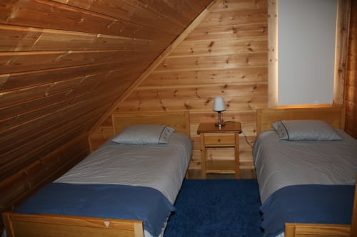 Acolhedor quarto de chalé em Cota 1500 com camas individuais, paredes de madeira e vistas para a montanha em Penhas da Saúde