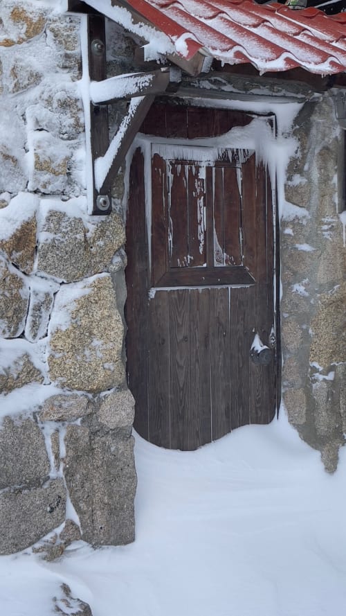 Entrada de porta de madeira coberta de neve do chalé Cota 1500 em Penhas da Saúde durante o inverno