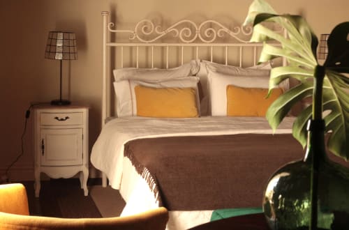 Elegant bedroom at Villa Várzea with ornate bed, golden pillows, and potted plant in Várzea, Portugal