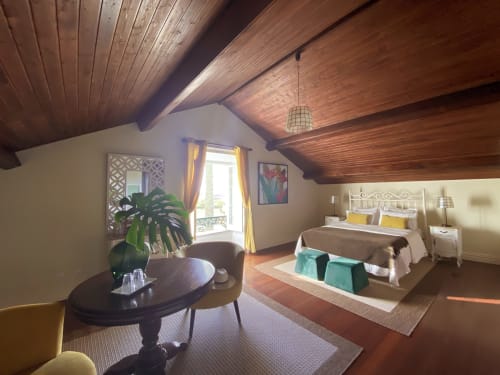 Spacious attic bedroom at Villa Várzea with wooden beams, vaulted ceiling, double bed, seating area, and balcony access in