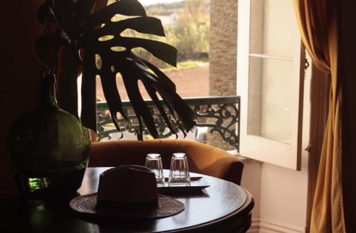 Elegant dining table at Villa Várzea with monstera plant, glass glasses, and Várzea countryside view through balcony doors.