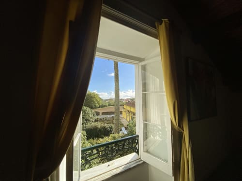 Open French doors with golden curtains at Villa Várzea overlooking palm tree and Várzea landscape