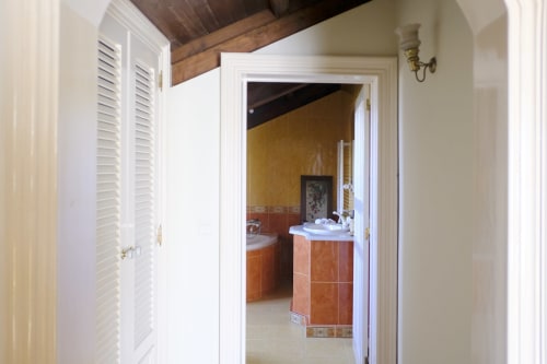 Hallway entrance to bathroom at Villa Várzea guesthouse in Várzea, Portugal, featuring white doors and terracotta tilework.