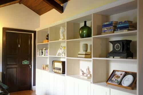 Villa Várzea study with white built-in shelving displaying books, vintage clock, and decorative objects