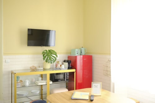 Colorful kitchenette at Villa Várzea with yellow walls, red retro fridge, and flat-screen TV in Várzea