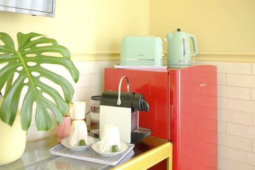 Colorful kitchen station at Villa Várzea with red mini-fridge, mint kettle, coffee machine, and green monstera plant