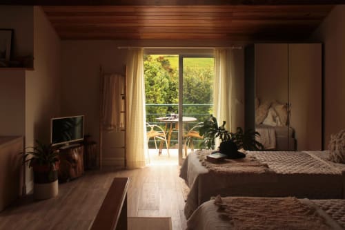 Bright bedroom at Villa Várzea B&B in Várzea, Portugal, with twin beds, balcony view, wooden floors, and garden landscape.