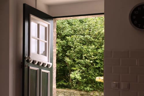Open black door at Villa Várzea BnB reveals lush green garden and ivy-covered walls in Várzea, Portugal