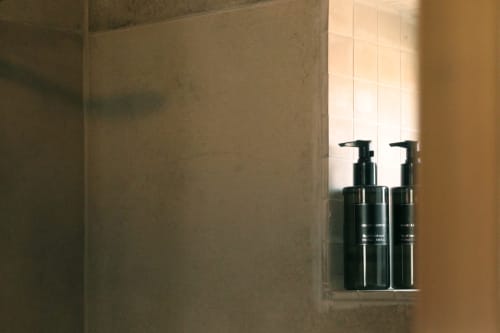 Two black pump bottles on tiled bathroom shelf at Villa Várzea boutique bed and breakfast in Várzea, Portugal