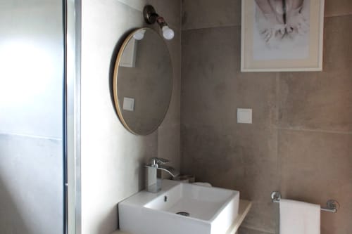 Modern bathroom sink with round mirror and vanity light at Villa Várzea guesthouse in Várzea, Portugal
