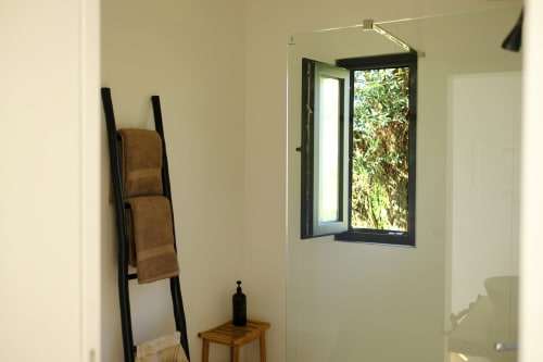 Modern bathroom at Villa Várzea with ladder shelf, open window overlooking garden, and minimalist decor in Várzea