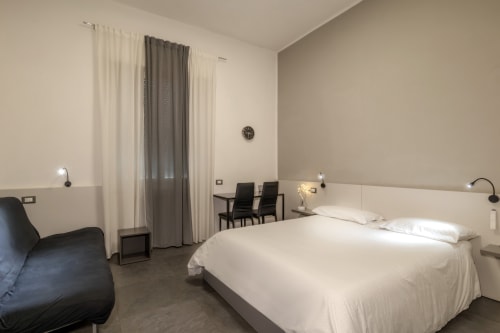 Modern bedroom at Casa Mirko in Arezzo with queen bed, seating area, and large windows with curtains