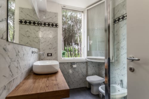 Bagno in marmo della Casa Mirko B&B ad Arezzo con lavabo d'appoggio, WC, doccia e finestra con vista sugli alberi