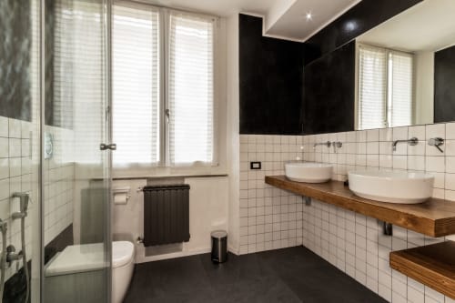 Modern bathroom in Casa Mirko B&B Arezzo with white tile walls, black ceiling, wood vanity with dual sinks, and glass shower