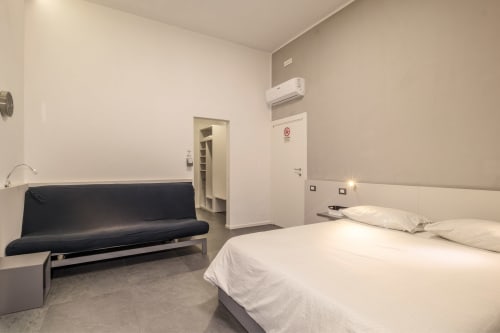 Modern bedroom at Casa Mirko B&B in Arezzo with double bed, black futon sofa, air conditioning and minimalist design