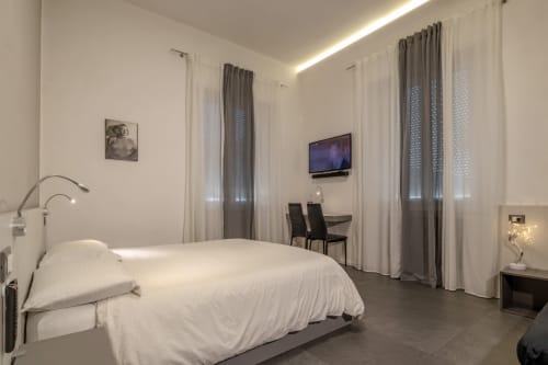 Modern bedroom at Casa Mirko in Arezzo with white bed, TV, and floor-to-ceiling curtains