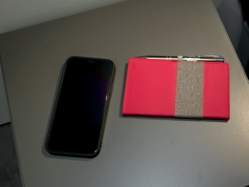 Black smartphone and red wallet with gray stripe on beige surface at Casa Mirko guesthouse in Arezzo