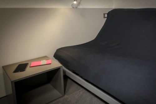 Modern bedroom at Casa Mirko in Arezzo with black upholstered bed, desk with phone and pink notepad, minimalist decor