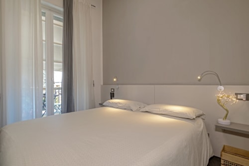 Modern bedroom at Casa Mirko B&B in Arezzo with white bedding, balcony access, and ambient lighting