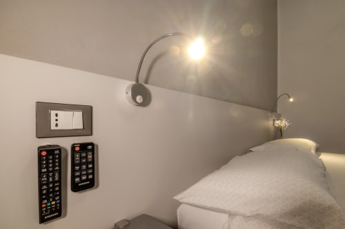 Casa Mirko bedroom in Arezzo with white pillows, arc lamp, wall switch, remote controls, and modern amenities