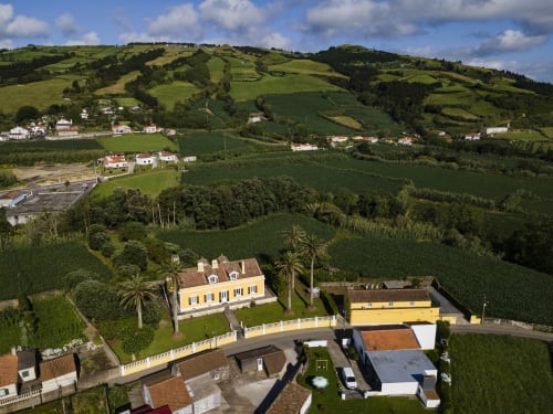 Villa Várzea bed and breakfast with yellow buildings set in lush green hills of Várzea, Portugal