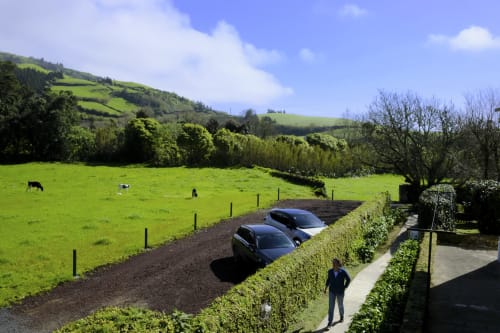 Villa Várzea driveway with parked cars, lush green fields, and rolling hills in Várzea, Portugal