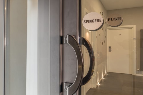 Glass door with handles at Casa Mirko B&B in Arezzo, featuring Italian signage reading 'Spingere' and 'Push'
