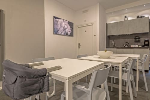 Modern dining and kitchen area at Casa Mirko B&B in Arezzo with white table, gray chairs, and wolf artwork on wall
