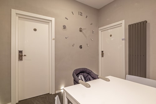 Modern bedroom at Casa Mirko B&B in Arezzo with wall clock, white doors, and minimalist decor