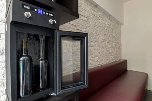 Modern wine cooler with bottles at Casa Mirko B&B in Arezzo, featuring brick wall and burgundy seating
