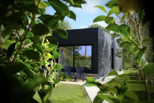 Modern black cubic guest pavilion at Villa Várzea with large windows, Adirondack chairs, and lush green gardens in Várzea,
