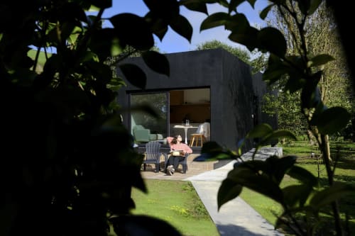 Modern black cabin at Villa Várzea with guest relaxing on patio, framed by greenery in Várzea, Portugal