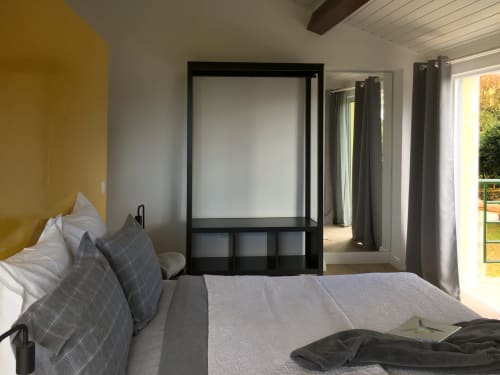 Modern bedroom at Villa Várzea with mustard accent wall, canopy bed, and glass doors opening to garden in Várzea