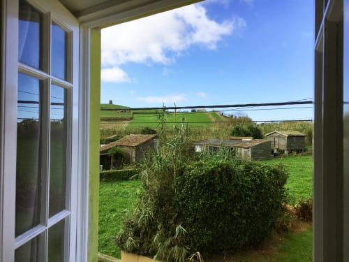 View from Villa Várzea window overlooking green fields, rural outbuildings, and countryside in Várzea, Portugal