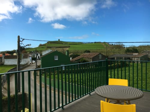 Villa Várzea patio with yellow chairs, green railing, and scenic green hillside views in Várzea, Portugal