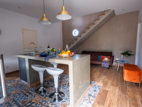 Villa Várzea Várzea BnB modern kitchen with island bar, brass pendant lights, and open living area with stairs