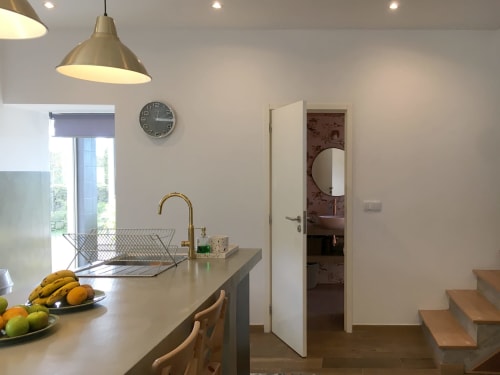 Modern kitchen at Villa Várzea with island counter, brass faucet, and open door to bathroom.