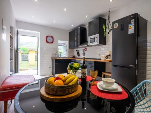 Modern kitchen at Villa Várzea's Hiker Nest with black appliances, dining area, and mountain view access in Várzea, Portugal