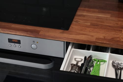 Modern kitchen drawer with utensils and green organizer in Villa Várzea's Hiker Nest room, showing wood countertop and stove