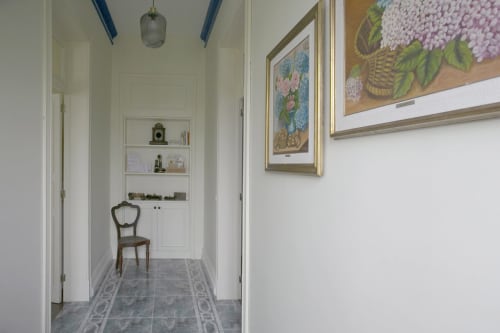 Elegant hallway at Villa Várzea with framed floral artwork, decorative chair, and tiled flooring leading to built-in shelving