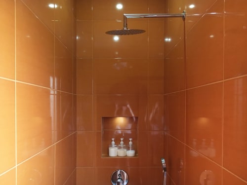 Modern orange tile shower with rainfall showerhead and amenities at Villa Várzea Design Nest room in Várzea, Portugal