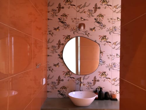 Modern bathroom in Design Nest at Villa Várzea with round mirror, white bowl sink, orange tile walls and botanical wallpaper,