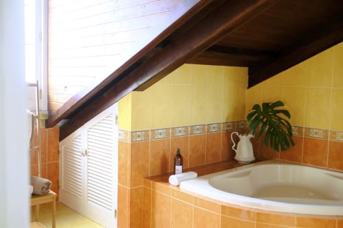 Charming Suite bathroom at Villa Várzea with yellow tile walls, curved bathtub, wooden beams, and mountain view window